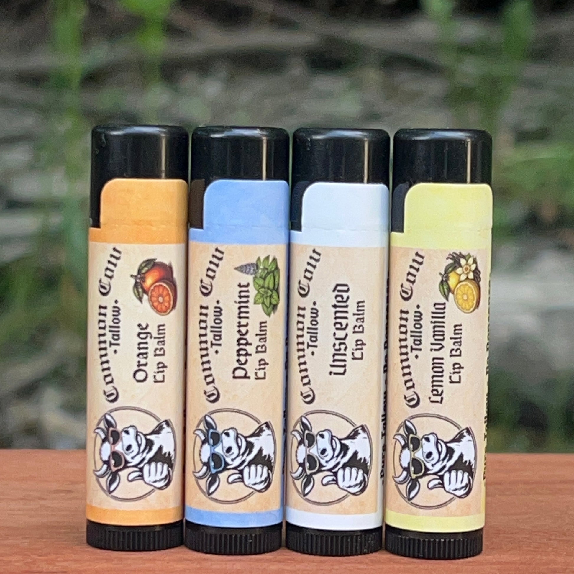 Four lip balm tubes with different scents on a wooden surface.