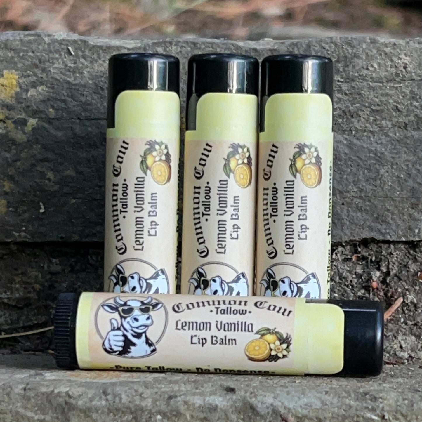 Four lip balms with visible branding on a stone surface