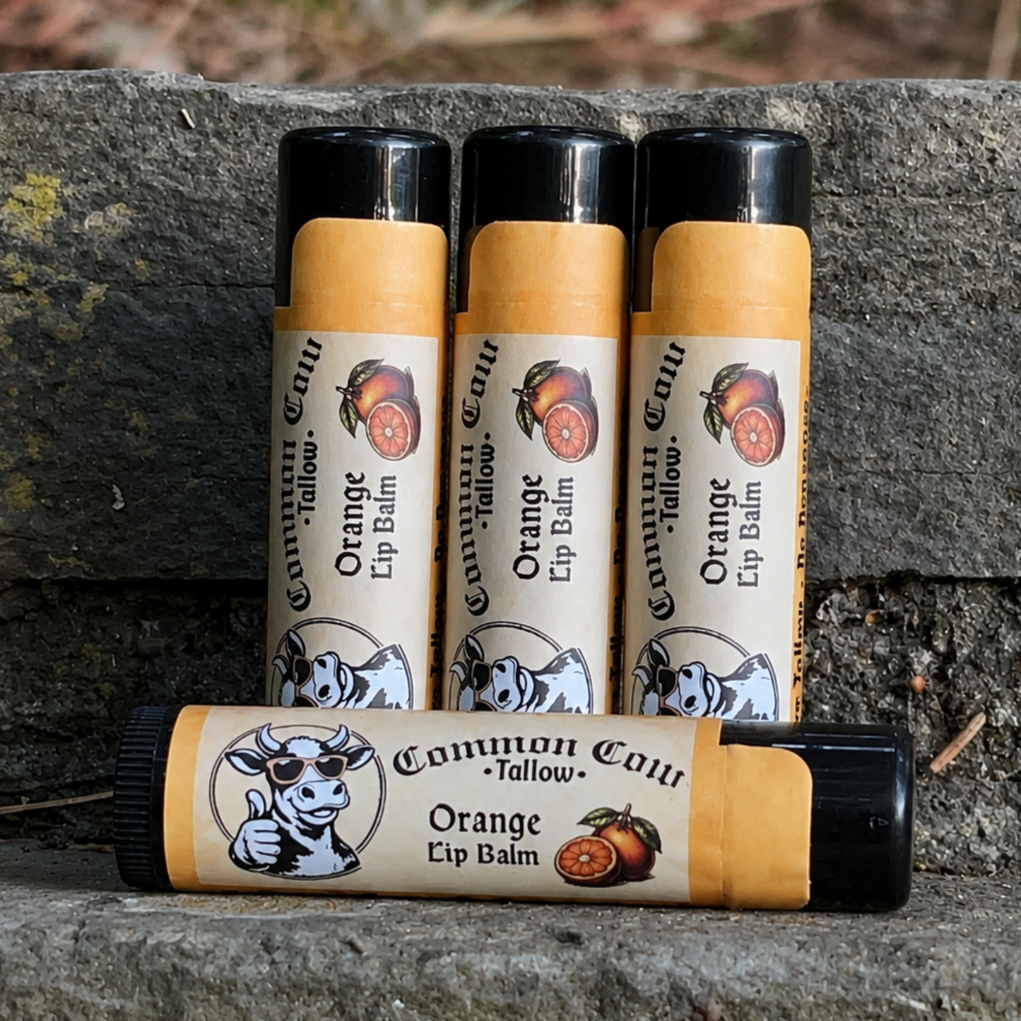 Four lip balms with visible branding on a stone surface.