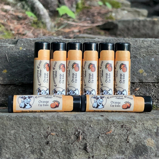 Multiple lip balm tubes stacked against a stone wall with natural background